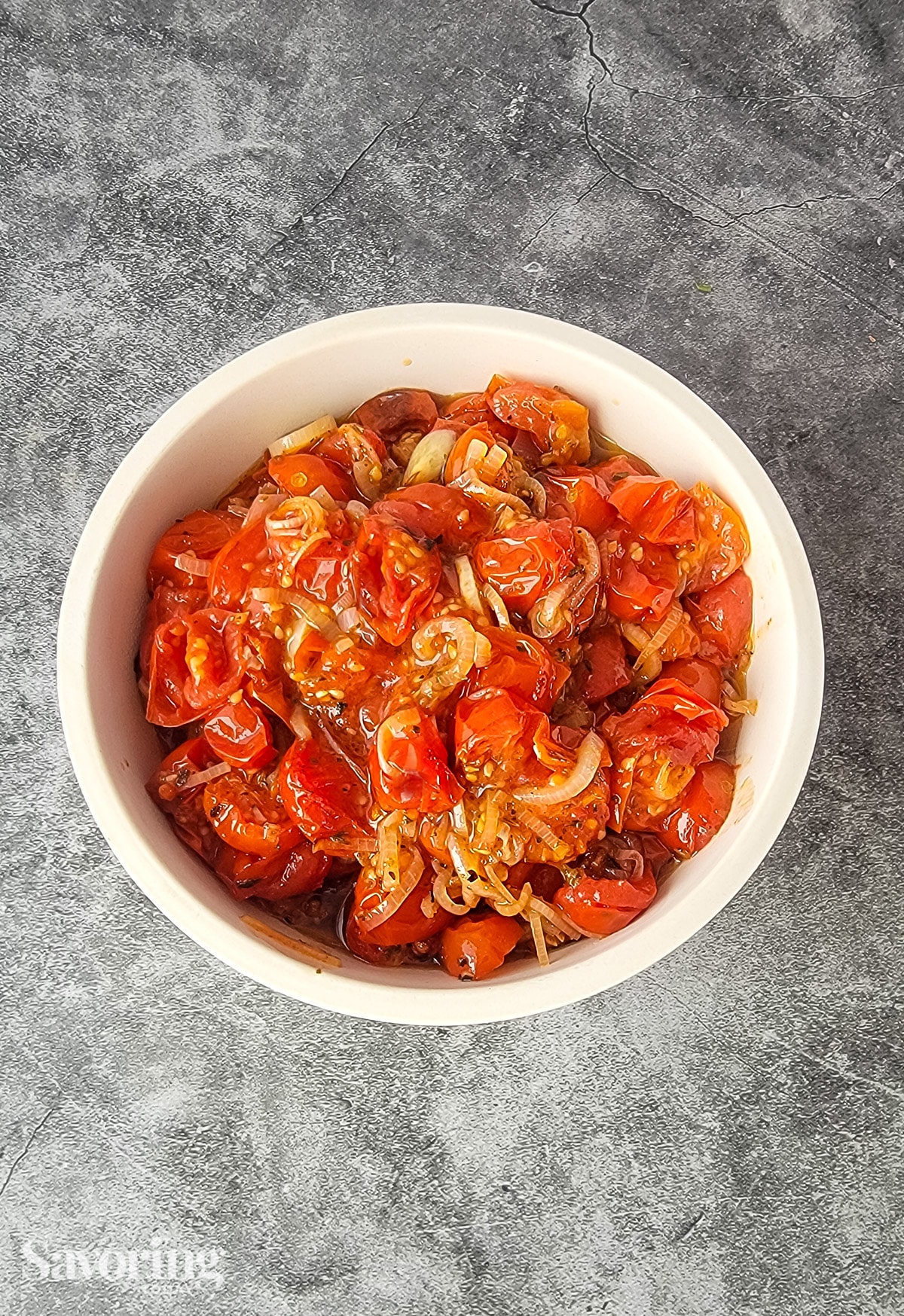 roasted tomato, shallots, and garlic in a white bowl on a grey countertop
