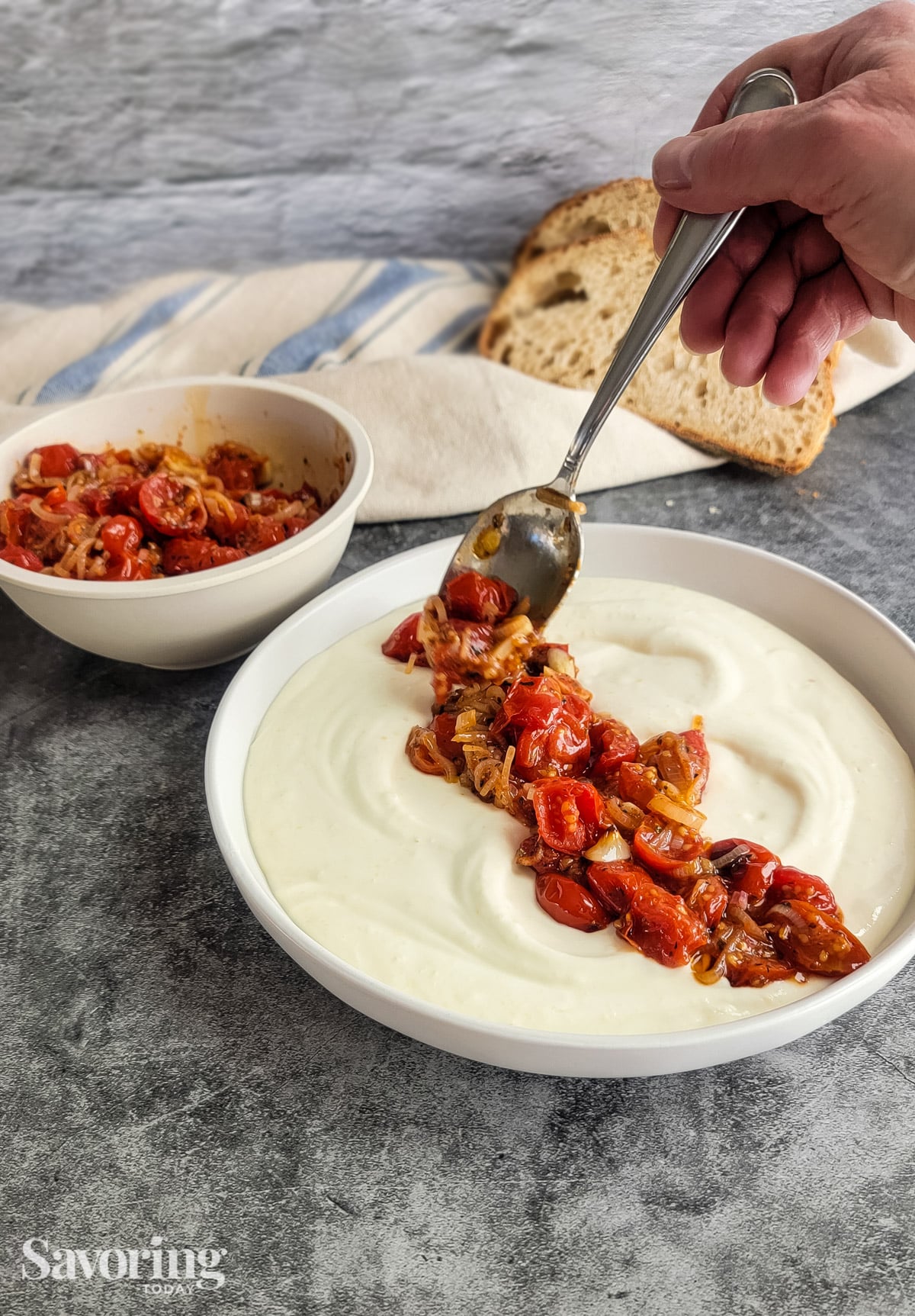 Spreading roasted tomatoes and shallots on whipped ricotta and feta dip