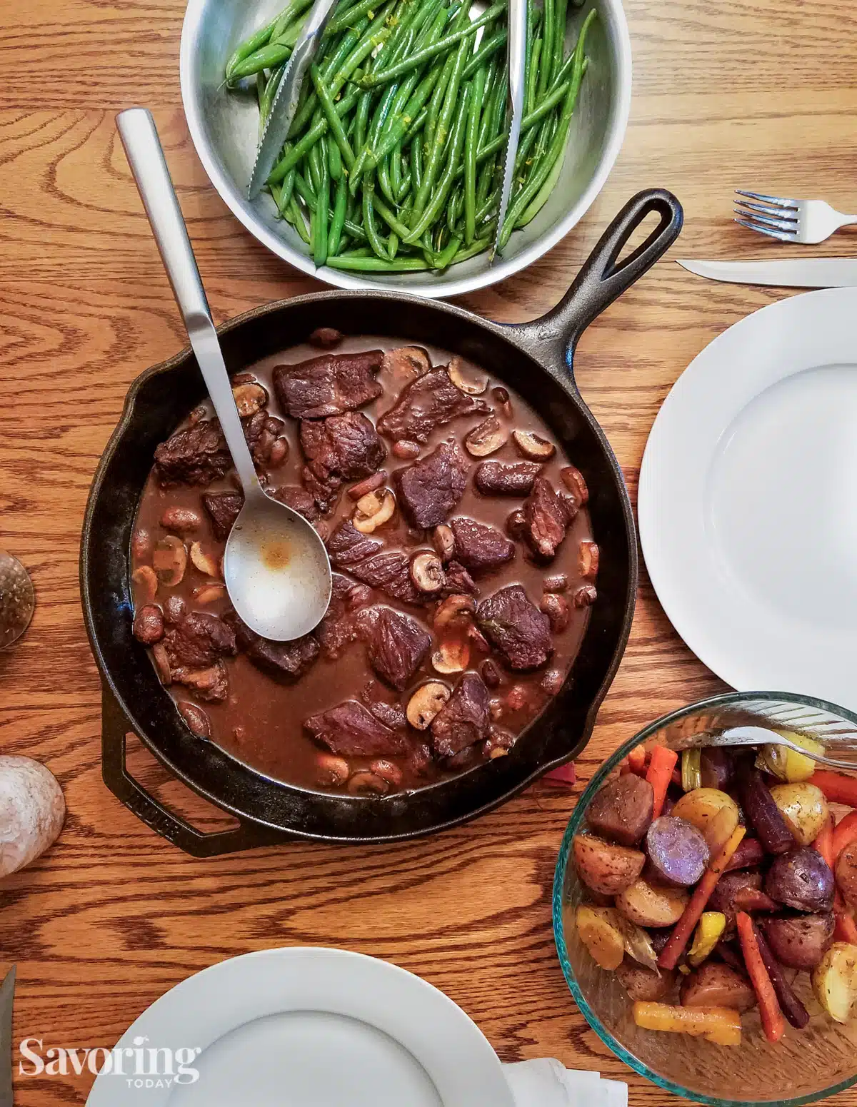 tablescape of beef roast with potatoes and carrots with a green bean side dish