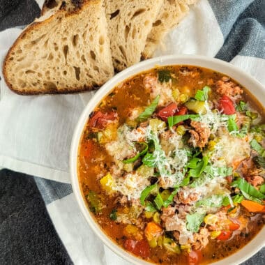 Italian sausage and split pea stew in a white bowl with bread on a towel