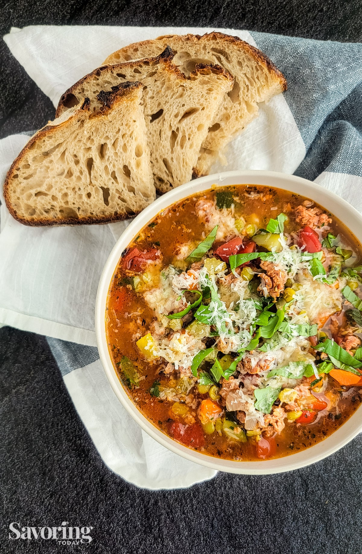 Italian sausage and split pea stew in a white bowl with bread on a towel