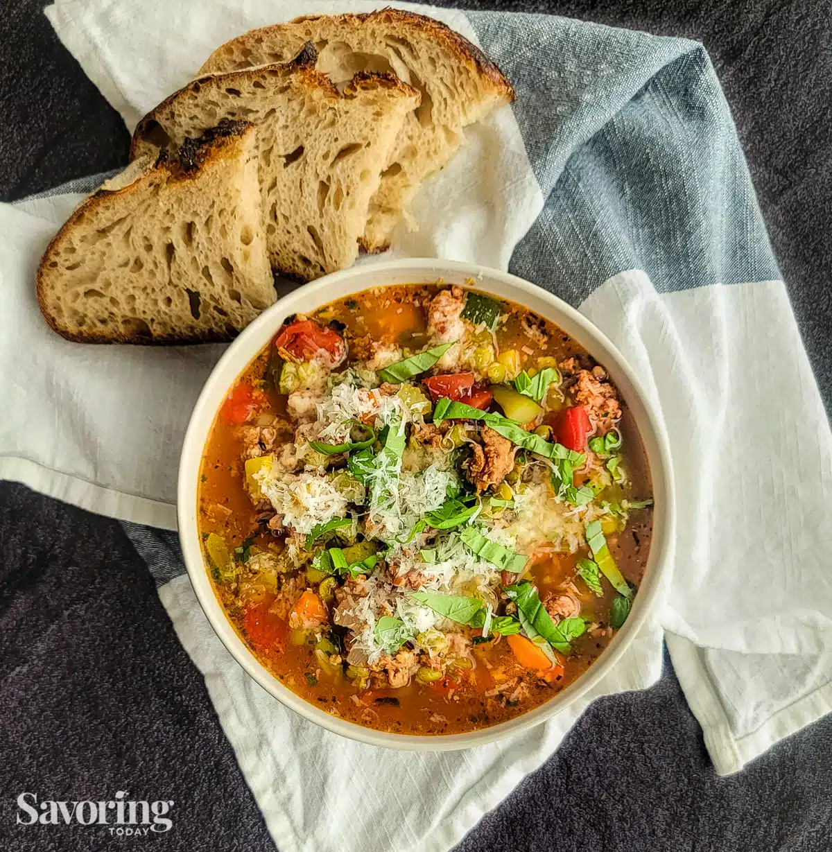 Split pea stew served in a white bowl set on a towel with bread