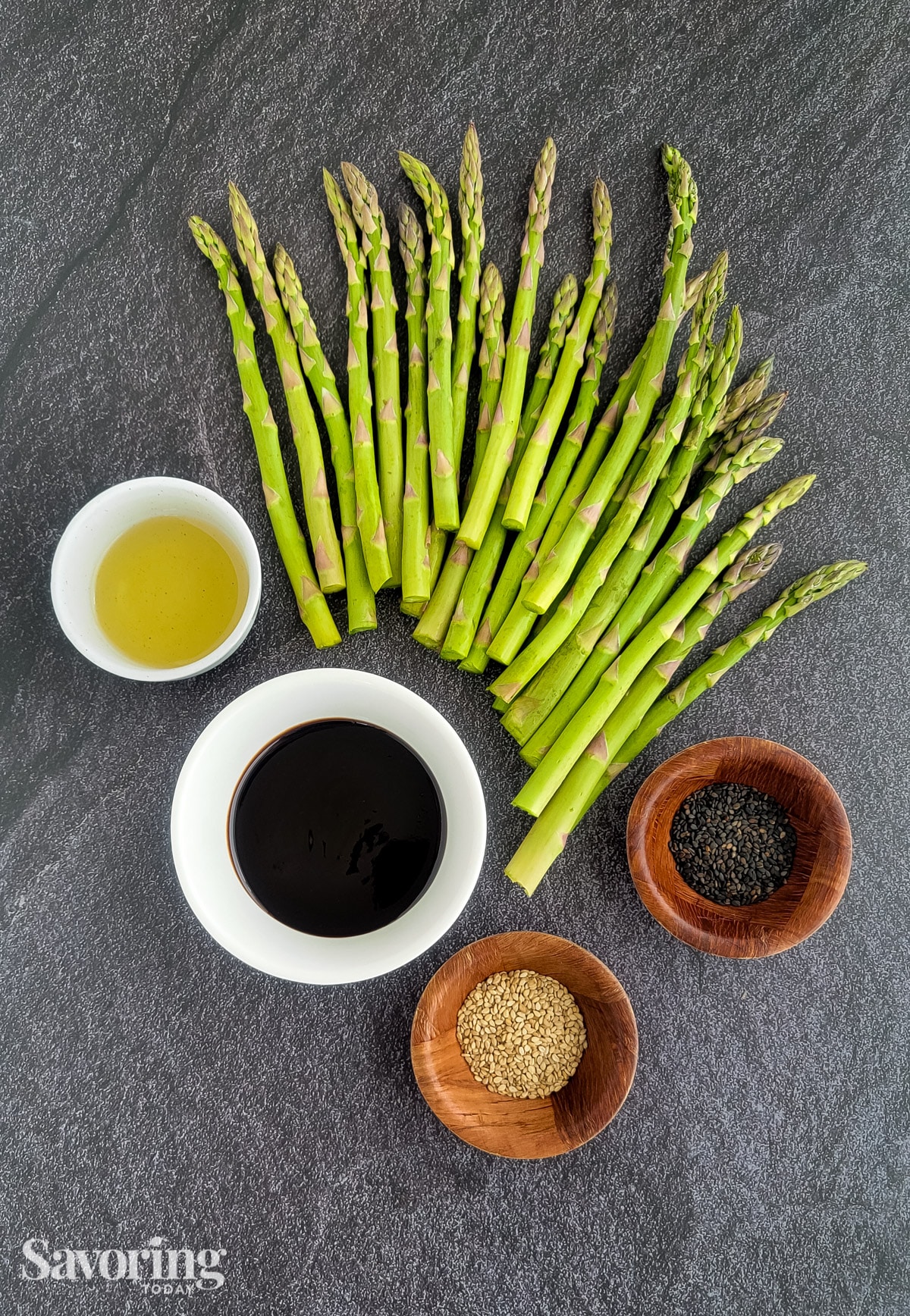 trimmed asparagus with oil, hoisin, and sesame seeds on a countertop