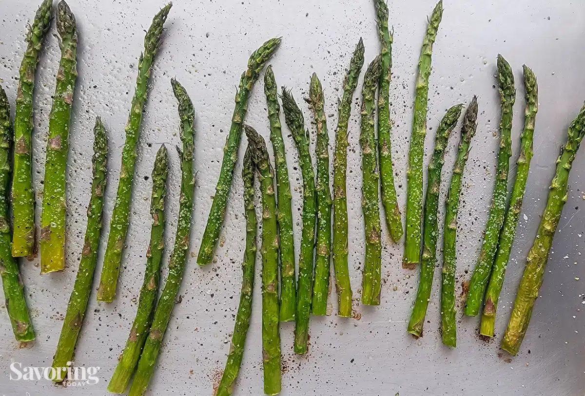 roasted asparagus seasoned with salt and pepper on a rimmed baking sheet