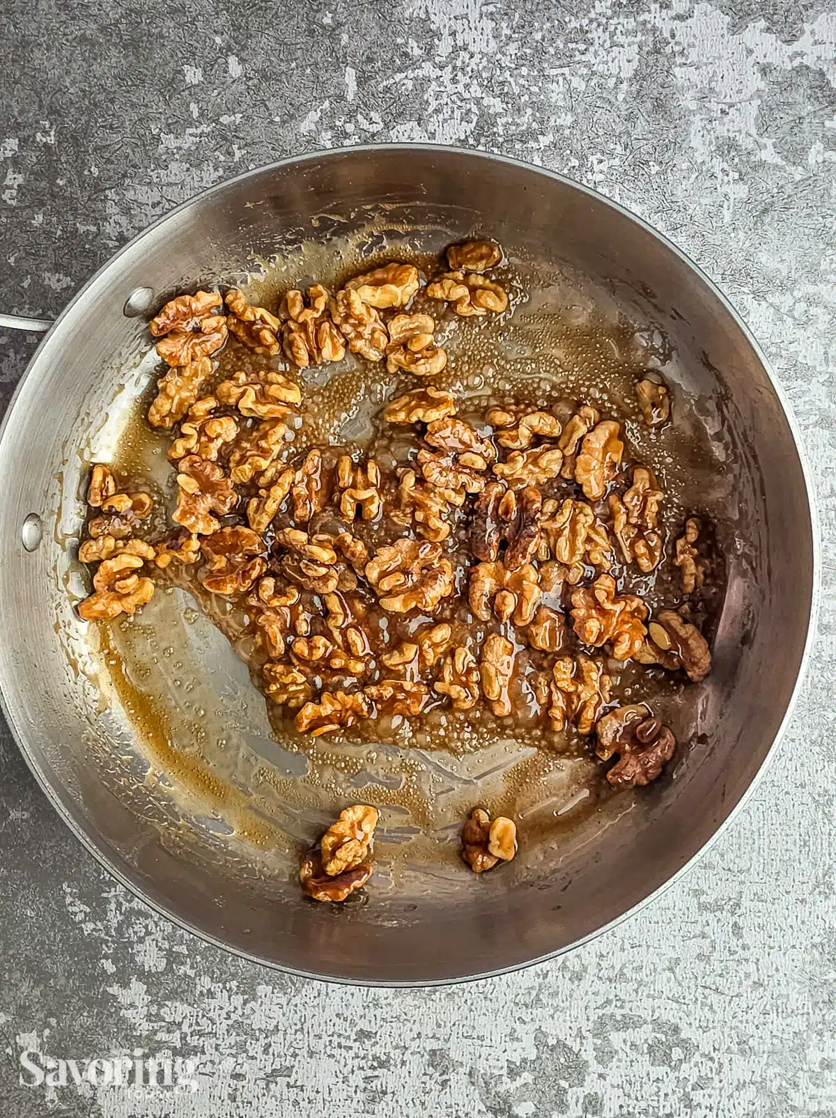 Candied walnuts in a stainless steel skillet