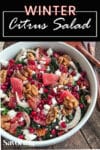 winter citrus salad with walnuts and feta cheese on a wood table with Pinterest banner