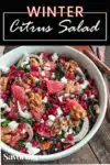 winter citrus salad with walnuts and feta cheese on a wood table with Pinterest banner