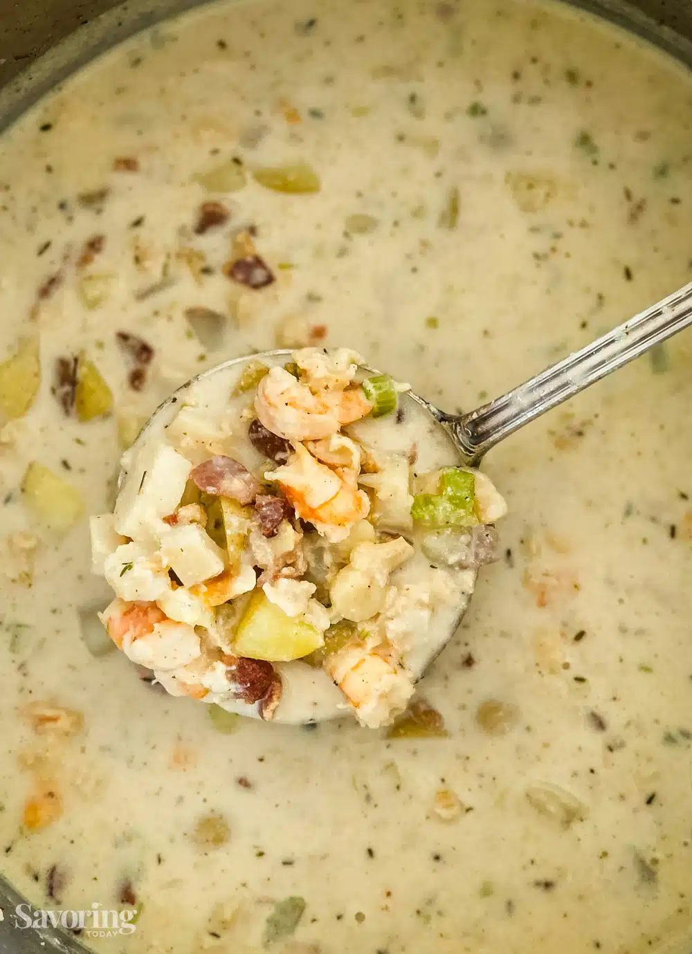 a ladle of seafood chowder held over the pot