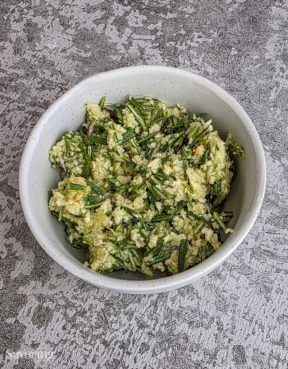 garlic and rosemary minced in a bowl for marinating beef