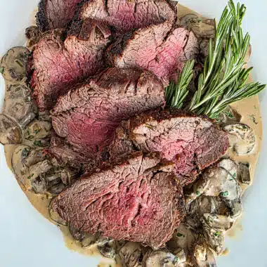 Grilled tenderloin on a bed of mushroom blue cheese sauce on a white plate