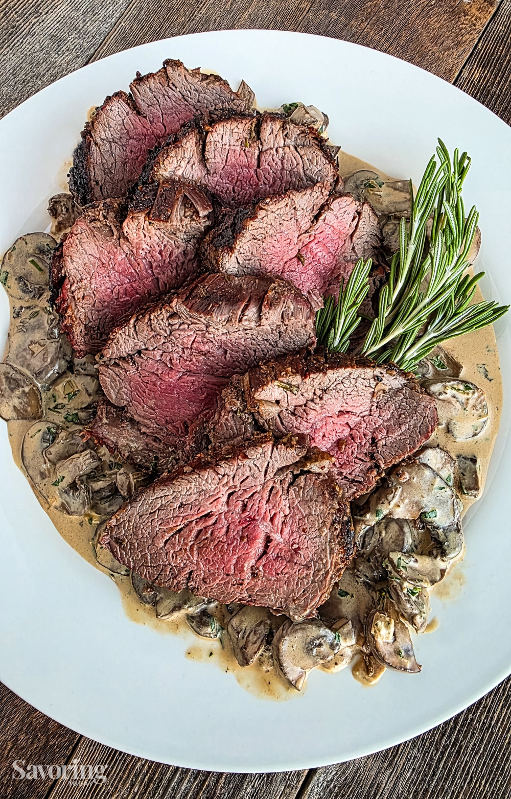 Grilled tenderloin on a bed of mushroom blue cheese sauce on a white plate