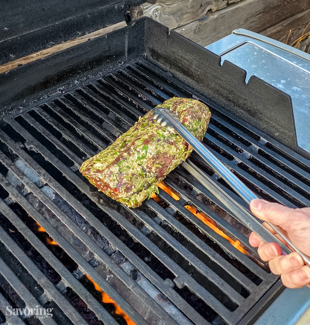 placing marinated tenderloin on a hot grill