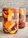 pickled carrots with ginger and sumac in a jar covered in brine