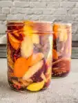 pickled carrots with ginger and sumac in a jar covered in brine