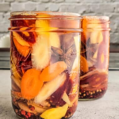 pickled carrots with ginger and sumac in a jar covered in brine